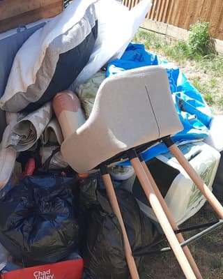 Before: a chair, cushions and bin bags piled against a shed